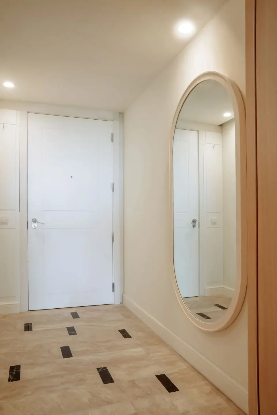 Pool View Suite entry hall with white door and oval wall mirror at JOIA Aruba.