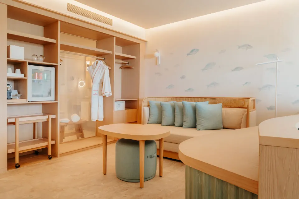 Swim-out suite sitting area with sofa bed and open wardrobe at JOIA Aruba.
