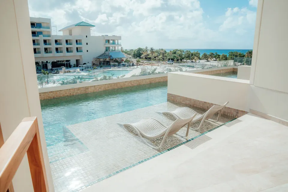Swim-out suite patio with loungers and pool access at JOIA Aruba.