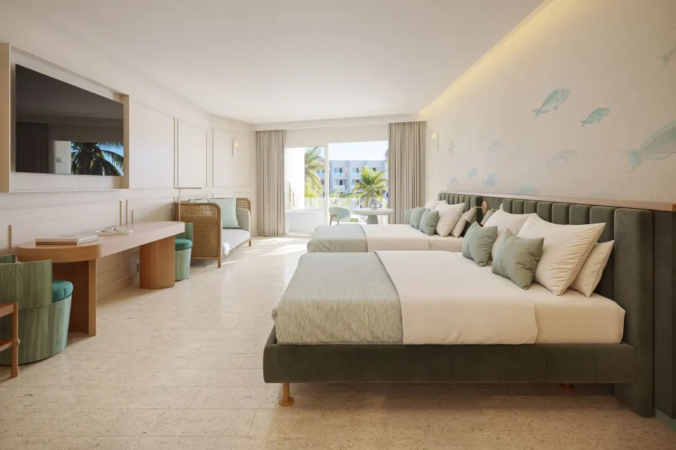 Suite with two beds, desk, sofa and balcony doors at JOIA Aruba.