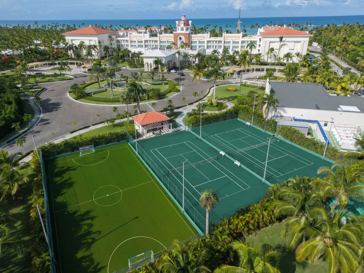 Aerial view of sports courts and the main resort building at JOIA Bávaro by Iberostar.