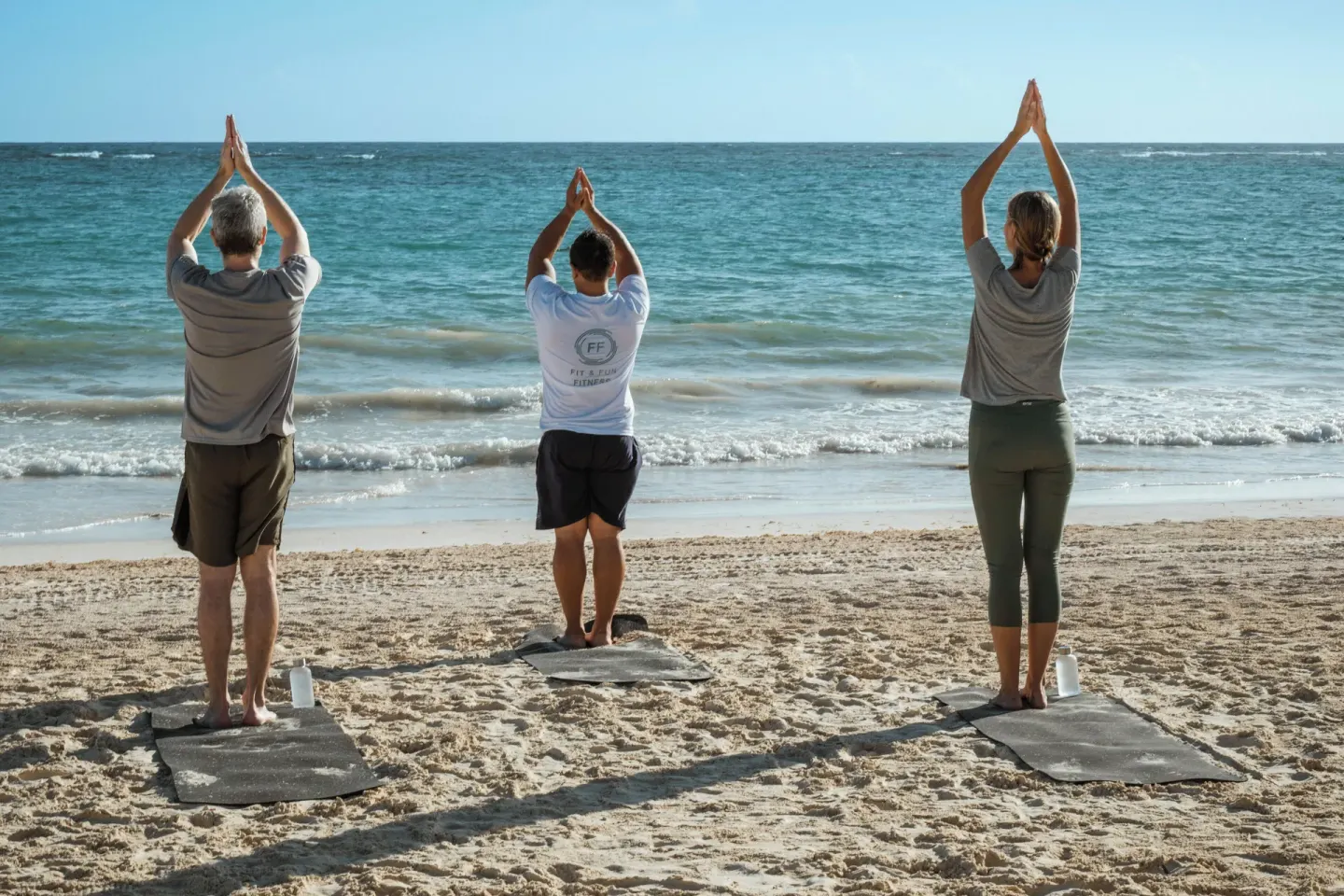 Three guests doing yoga on the beach at JOIA Bávaro by Iberostar.