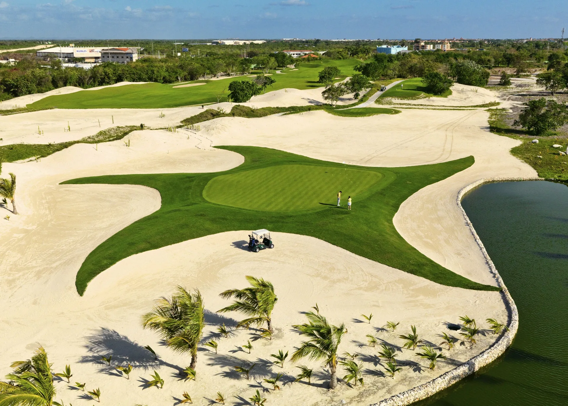 Aerial view of a golf green, sand areas, and water near JOIA Bávaro by Iberostar.