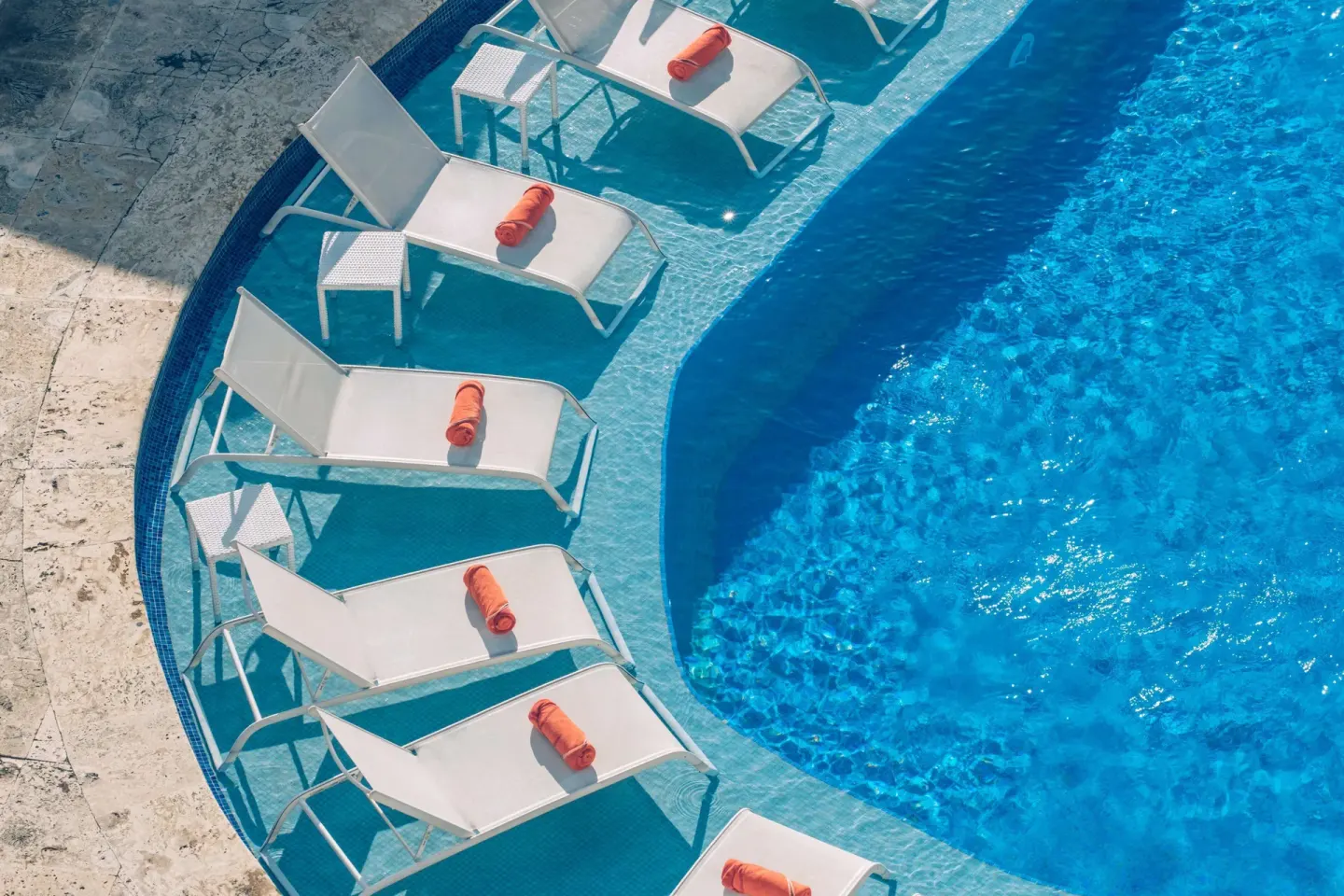 In-water pool loungers with orange towels at JOIA Bávaro by Iberostar.