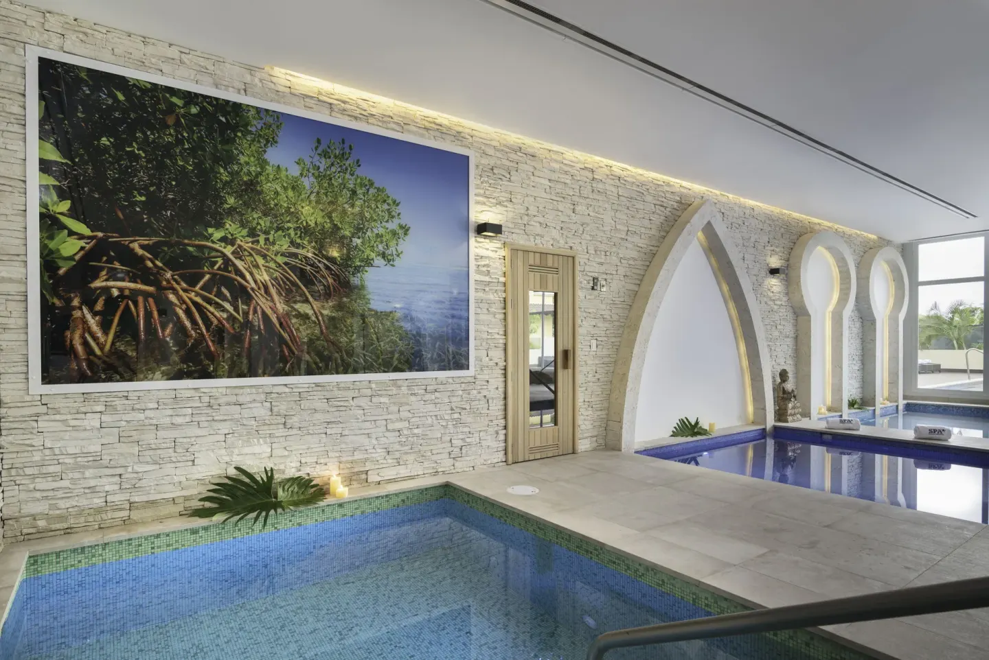 Indoor spa pool with stone walls and arched alcoves at JOIA Bávaro by Iberostar.