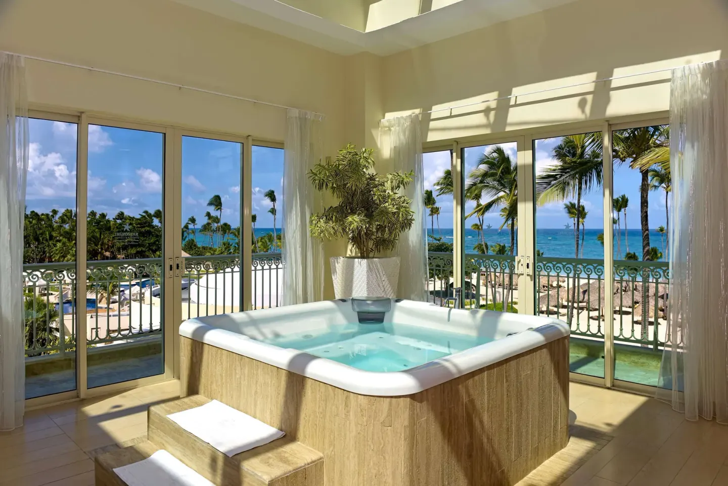 Sunlit indoor whirlpool with ocean and palm views at JOIA Bávaro by Iberostar.