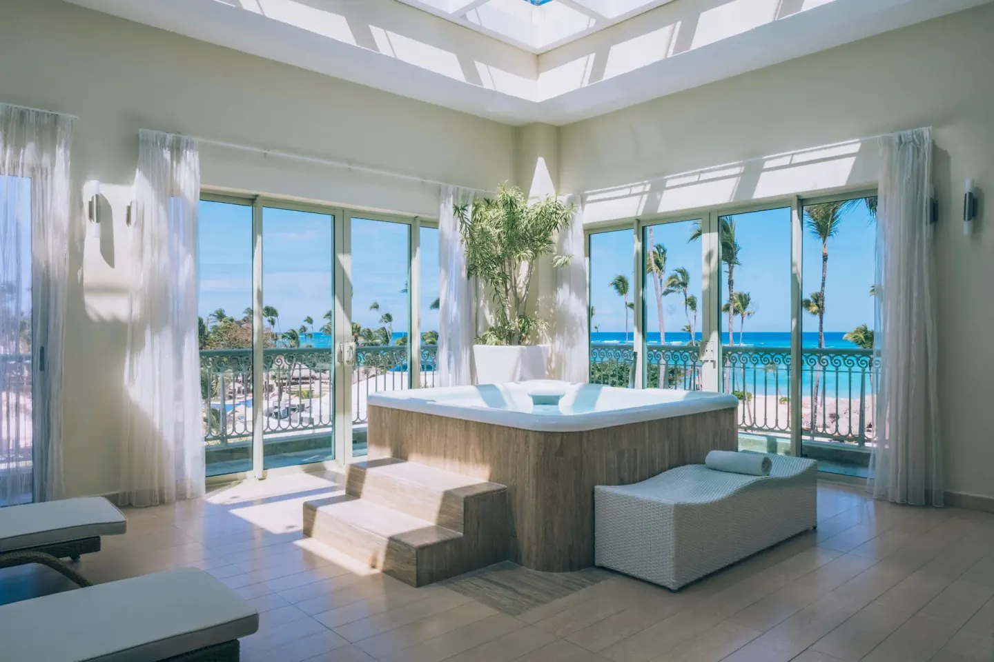 Spa suite with raised hot tub and ocean-facing windows at JOIA Bávaro by Iberostar.
