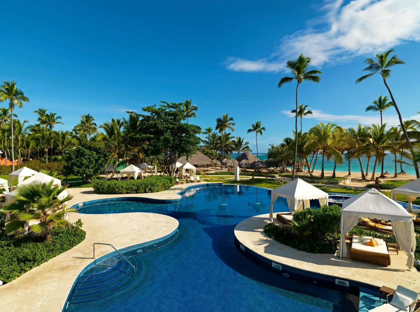 Aerial view of pool, cabanas, palms, and beach at JOIA Bávaro by Iberostar.