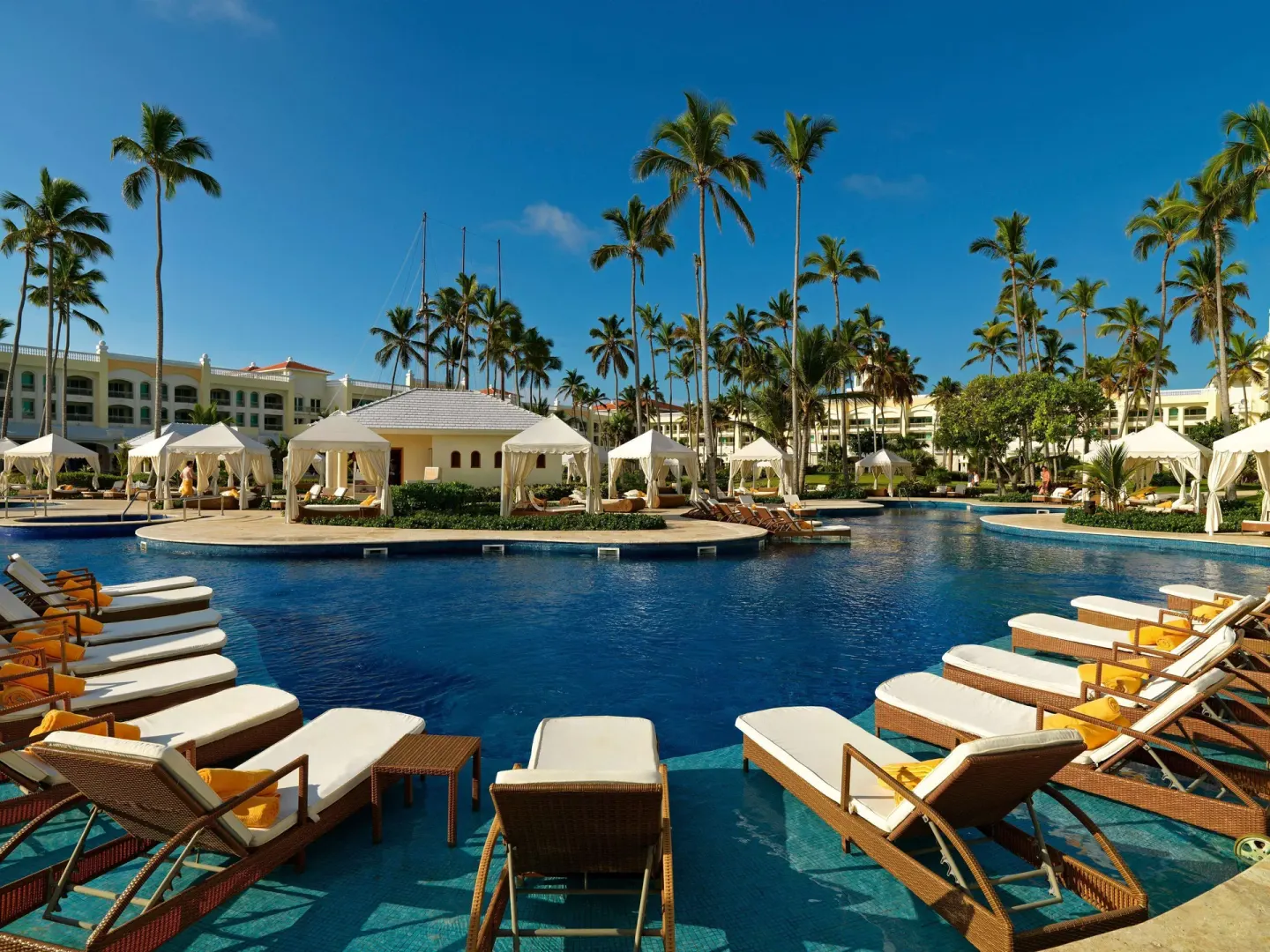 Pool deck with loungers, cabanas, and palms at JOIA Bávaro by Iberostar.