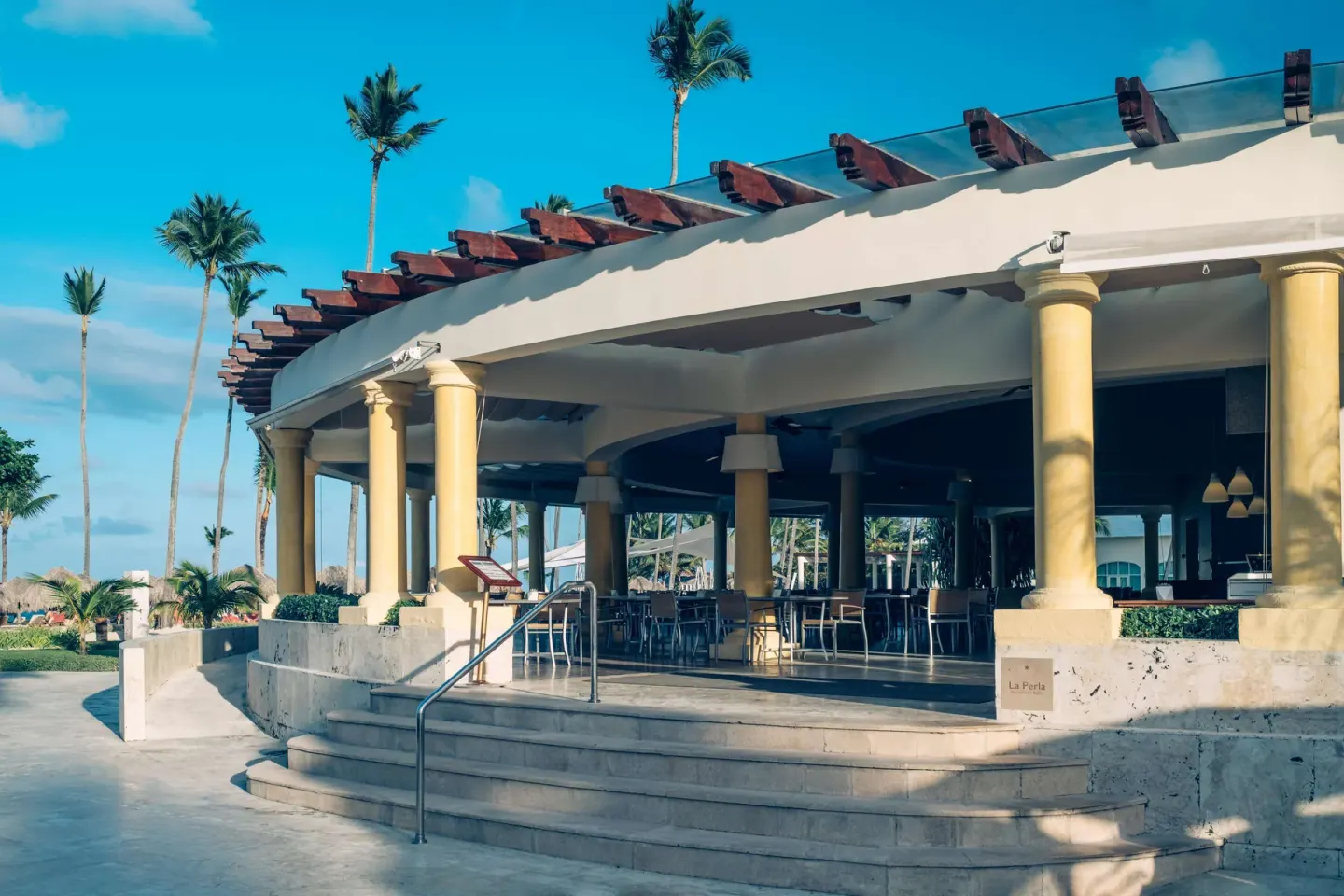 La Perla restaurant entrance with columns and open-air seating at JOIA Bávaro by Iberostar.