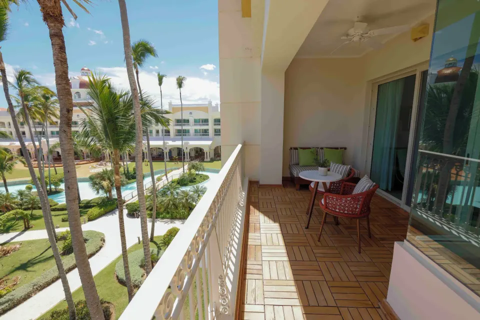 Suite Lake View balcony overlooking gardens and water at JOIA Bávaro by Iberostar.