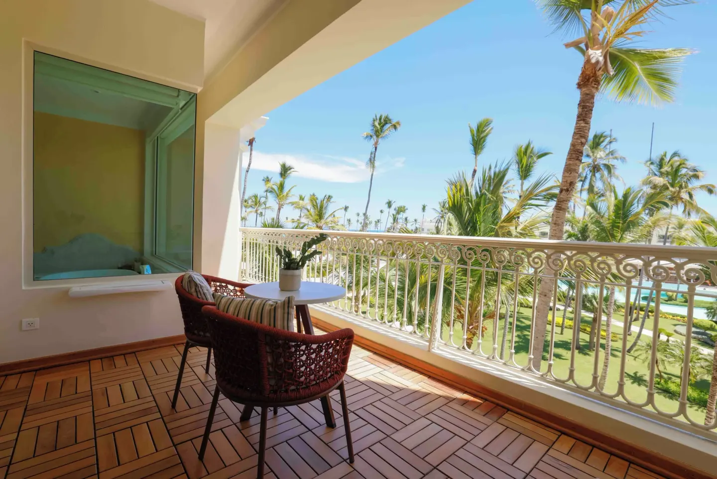 Suite Lake View balcony with table and palm views at JOIA Bávaro by Iberostar.