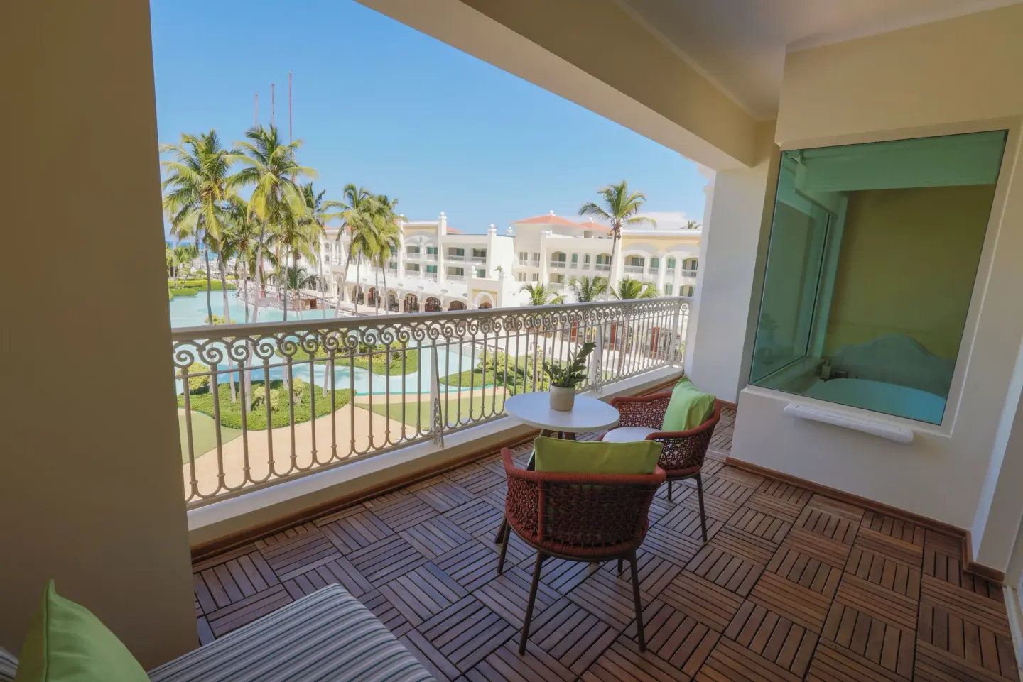 Ocean View Suite balcony with seating and resort grounds at JOIA Bávaro by Iberostar.