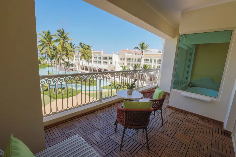 Ocean View Suite balcony with seating and resort grounds at JOIA Bávaro by Iberostar.
