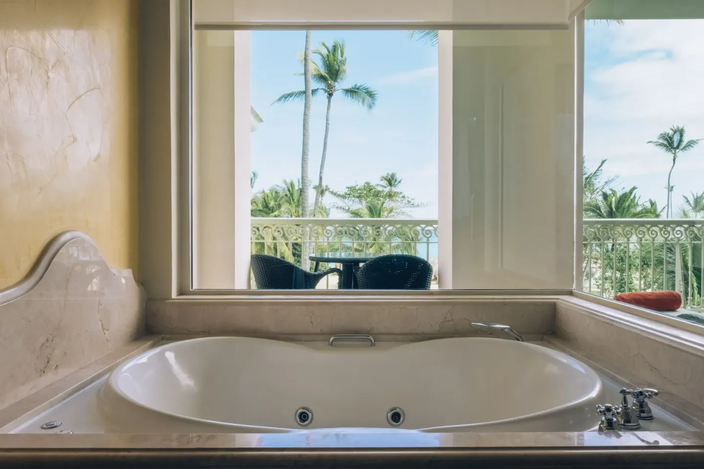 Oceanfront suite bathtub with balcony and palm view at JOIA Bávaro by Iberostar.