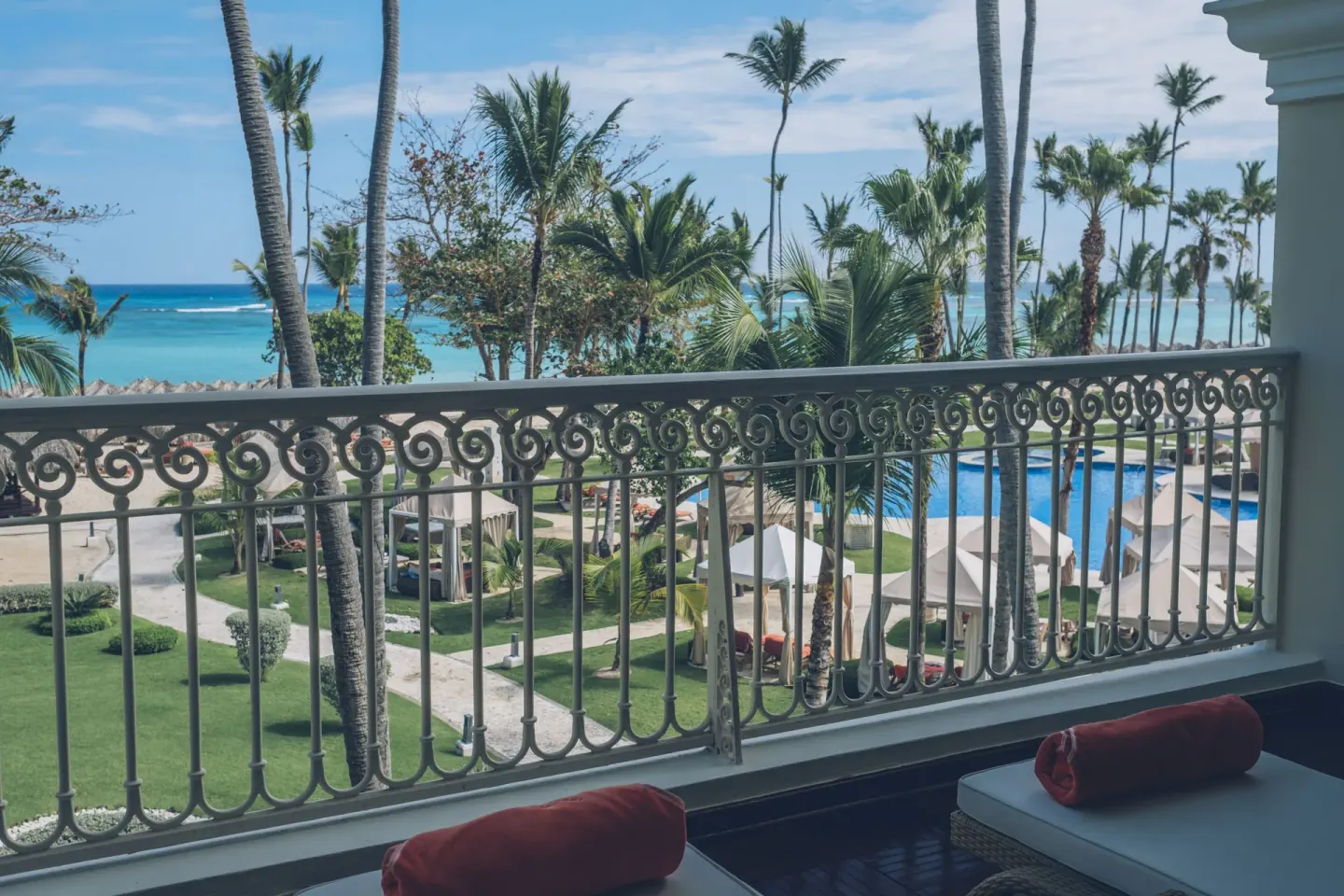 Oceanfront suite balcony view of beach, pool and palms at JOIA Bávaro by Iberostar.