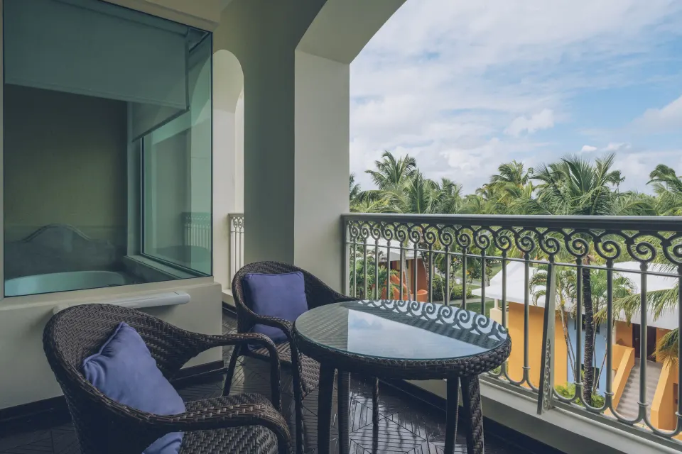 Suite upper floor balcony with wicker chairs at JOIA Bávaro by Iberostar.