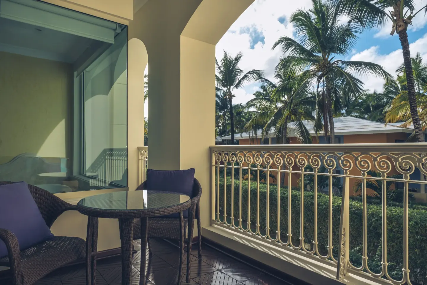 Suite balcony with wicker seating and palm garden views at JOIA Bávaro by Iberostar.