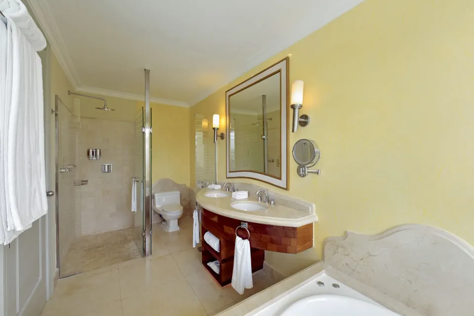 Suite bathroom with double vanity, bathtub and glass shower at JOIA Bávaro by Iberostar.