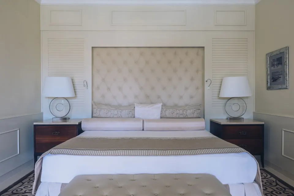 Suite king bed with tufted headboard and matching nightstands at JOIA Bávaro by Iberostar.