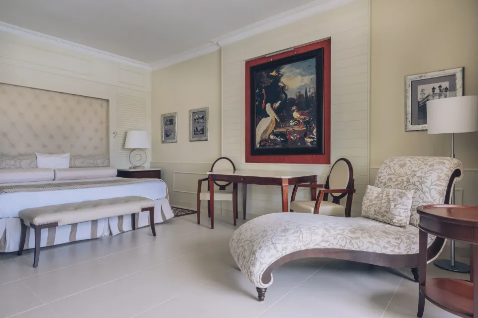 Suite seating area with king bed, chaise lounge and table at JOIA Bávaro by Iberostar.