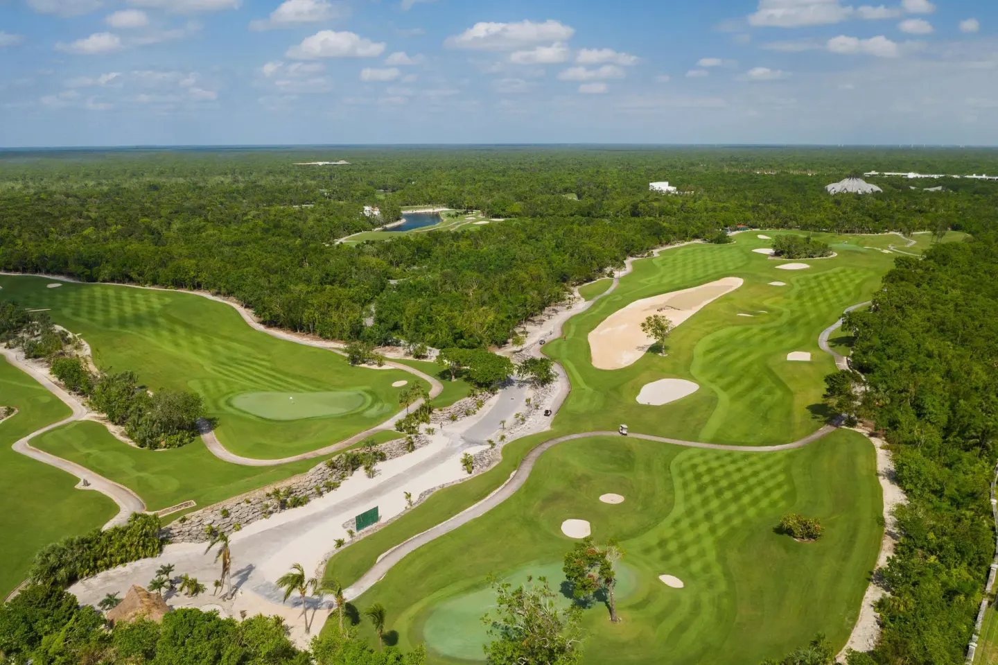Aerial view of the golf course near JOIA Paraíso by Iberostar with fairways, bunkers, and forest.