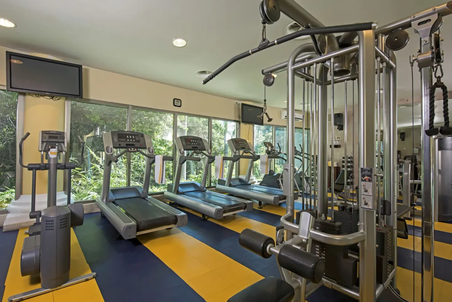 Fitness center with treadmills by garden-facing windows at JOIA Paraíso by Iberostar.