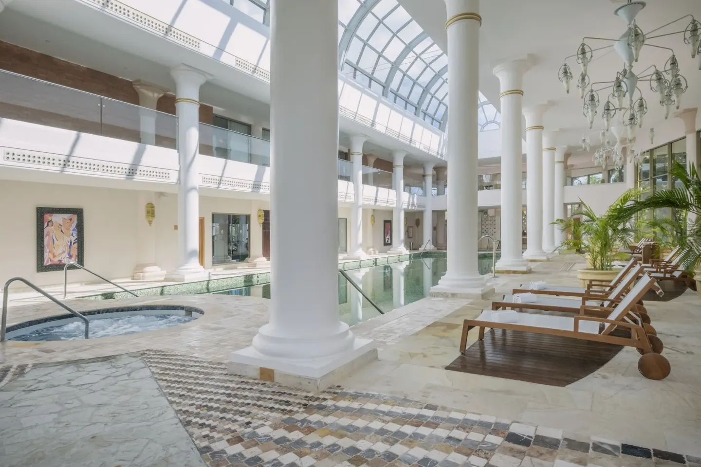 Indoor pool deck with columns and wooden loungers at JOIA Paraíso by Iberostar.