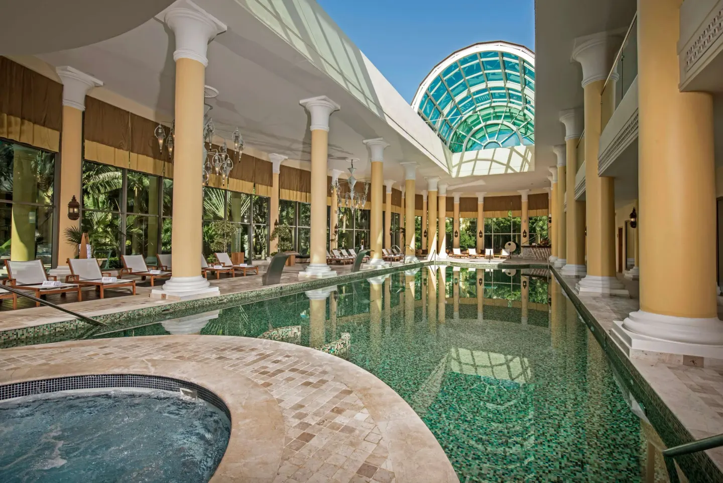 Indoor pool with columns, loungers and glass roof at JOIA Paraíso by Iberostar.
