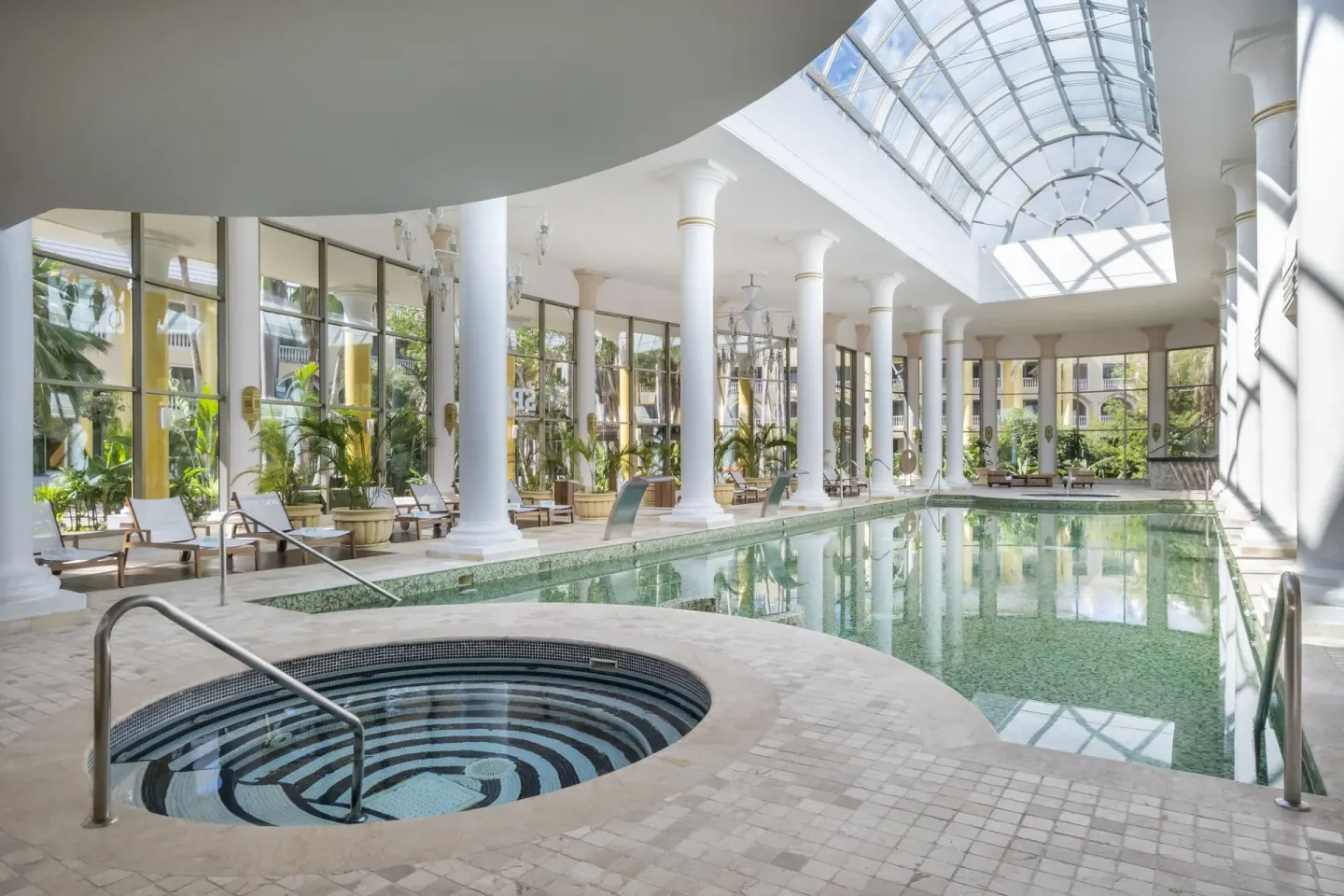 Indoor pool with skylight, columns, and lounge chairs at JOIA Paraíso by Iberostar.