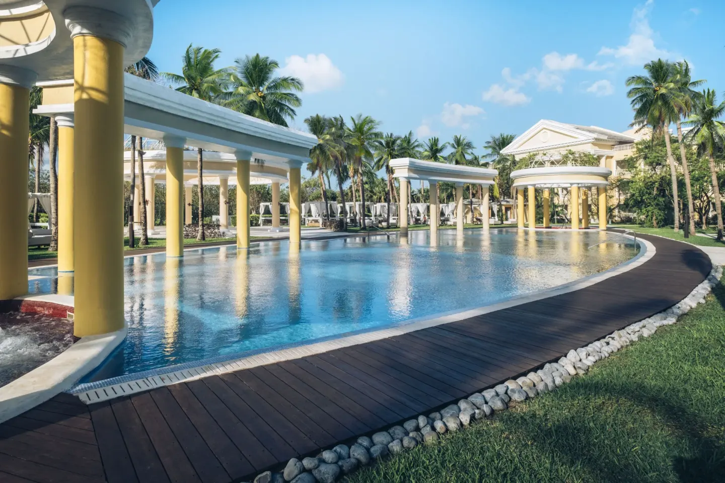 Long pool with colonnades, palms, and wooden walkway at JOIA Paraíso by Iberostar.