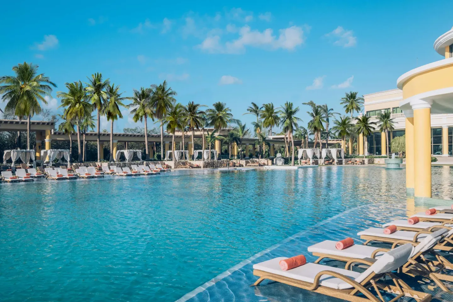 Large pool with loungers, palms, and cabanas at JOIA Paraíso by Iberostar.