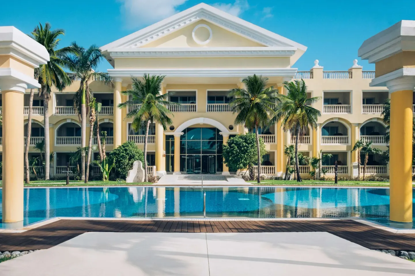 Yellow resort building reflected in a pool at JOIA Paraíso by Iberostar.