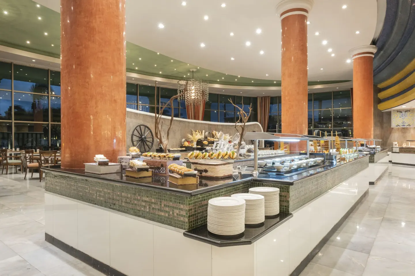 A buffet island with plates and food displays at JOIA Paraíso by Iberostar.