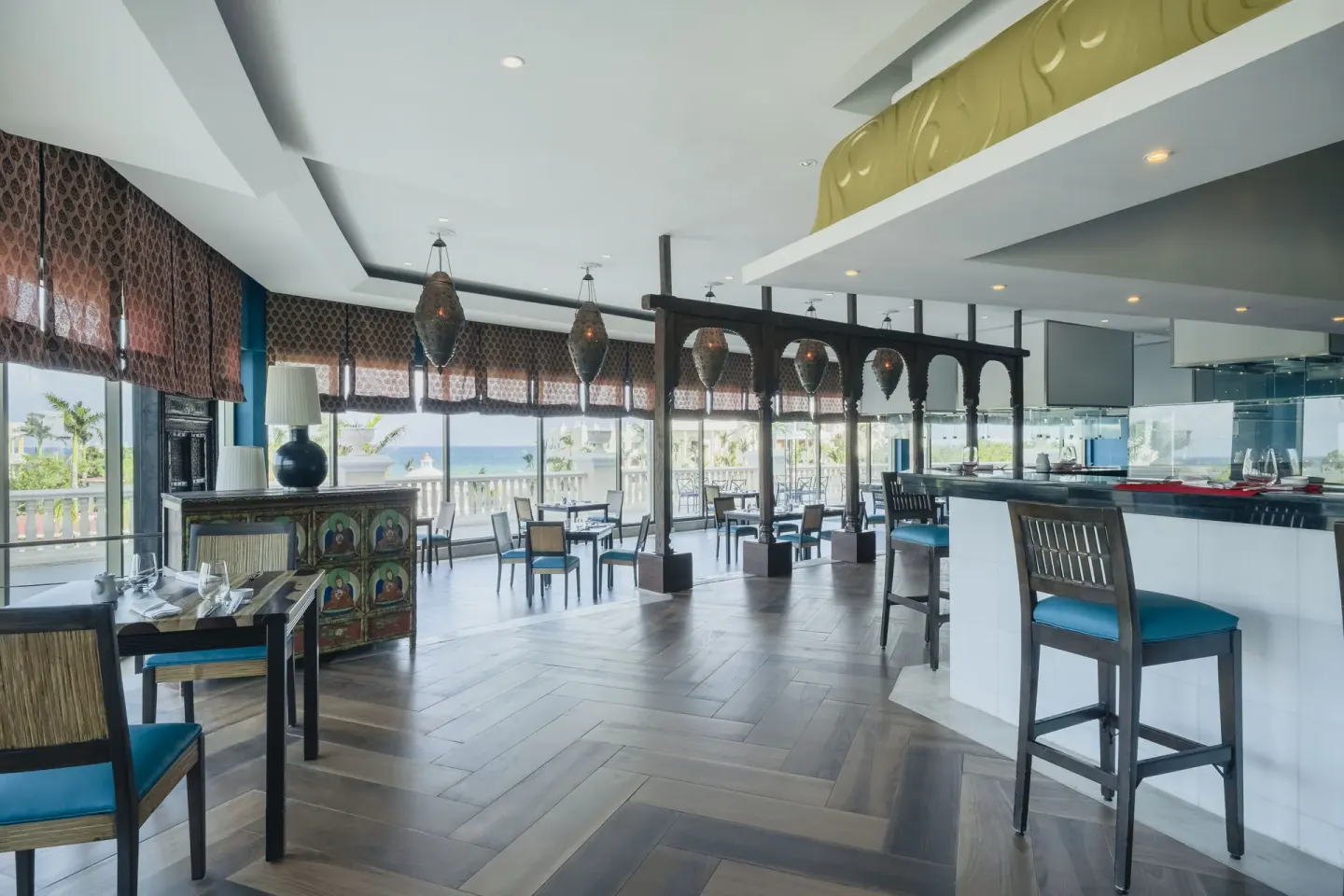 Ocean-view dining room at JOIA Paraíso by Iberostar with tables, high chairs, and a service counter.