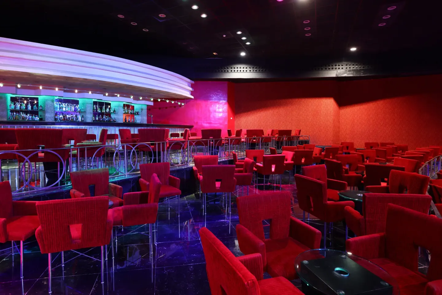 Red lounge bar with illuminated back bar and club seating at JOIA Paraíso by Iberostar.