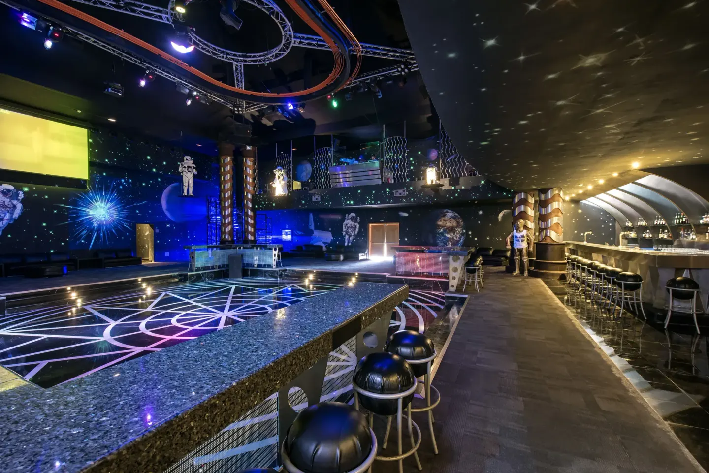 Space-themed bar and lounge at JOIA Paraíso by Iberostar with stage lighting and stools.