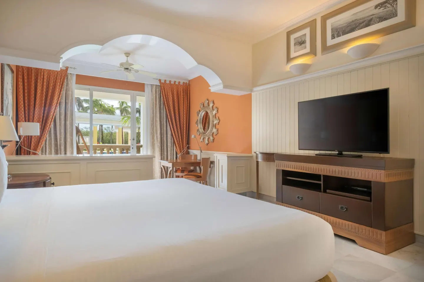 Suite bedroom with a king bed, TV, desk, and balcony at JOIA Paraíso by Iberostar.