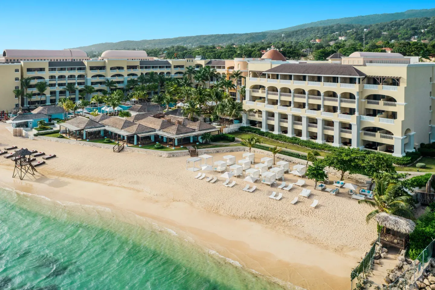 Beachfront resort buildings and cabanas beside the sea at JOIA Rose Hall by Iberostar.