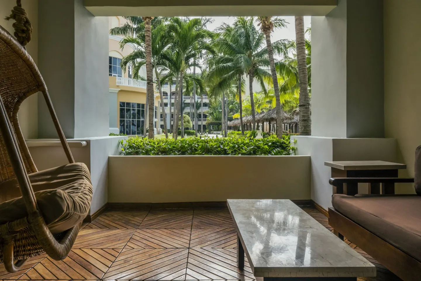 Garden-view terrace with hanging chair and lounge seating at JOIA Rose Hall by Iberostar.