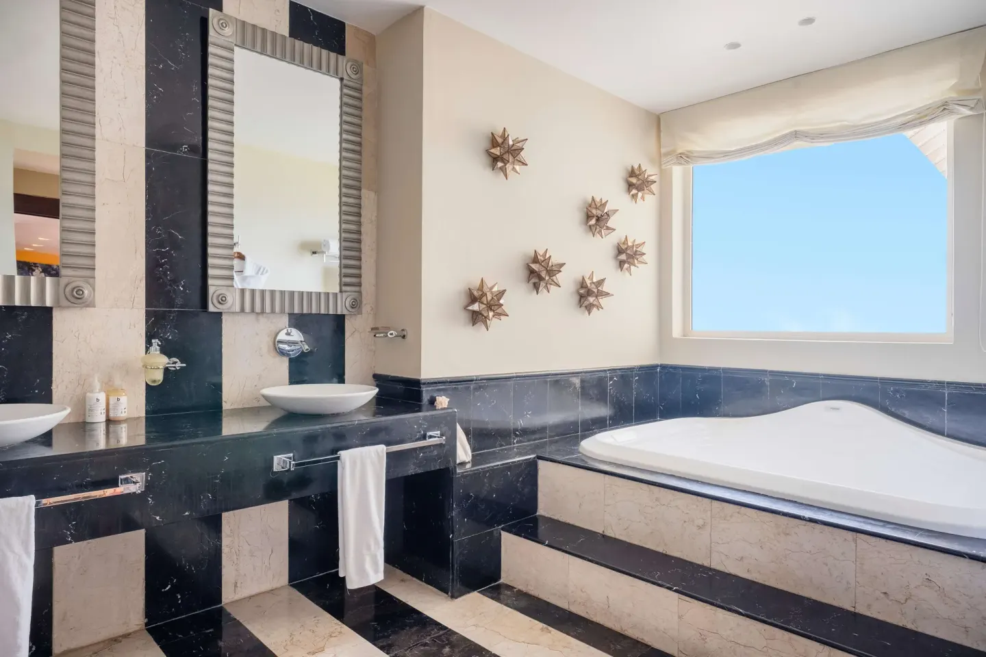 Guest bathroom with soaking tub and double vanity at JOIA Rose Hall by Iberostar.