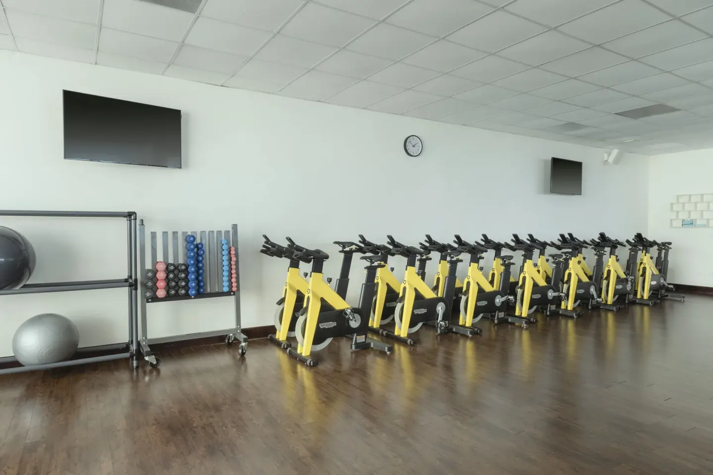 Indoor cycling studio with yellow spin bikes and exercise accessories at JOIA Rose Hall by Iberostar.