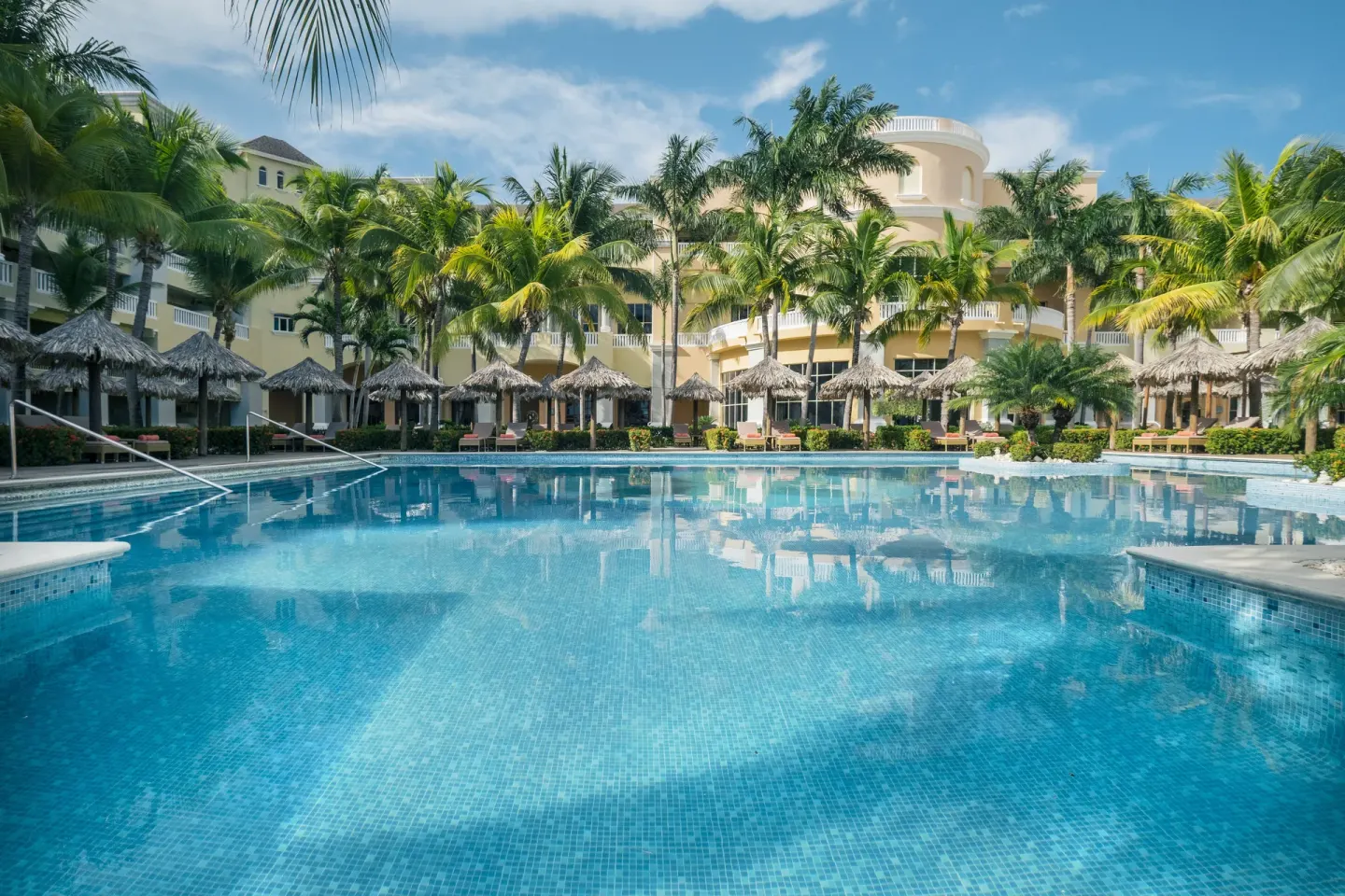 Large pool facing palms and resort buildings at JOIA Rose Hall by Iberostar.