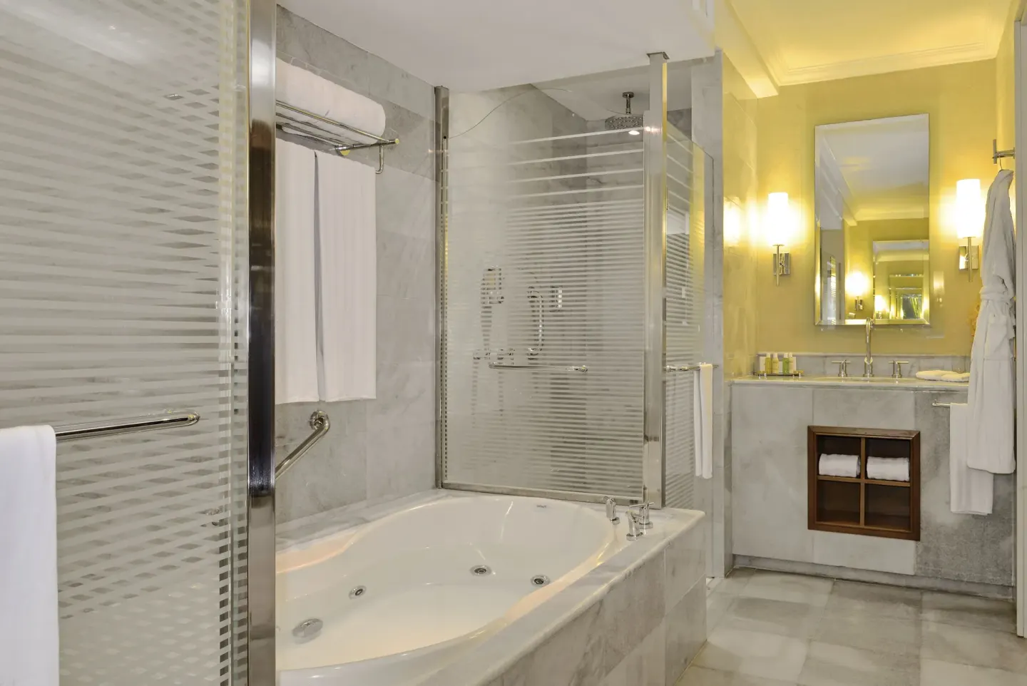 Marble bathroom with jetted tub and glass shower at JOIA Rose Hall by Iberostar.