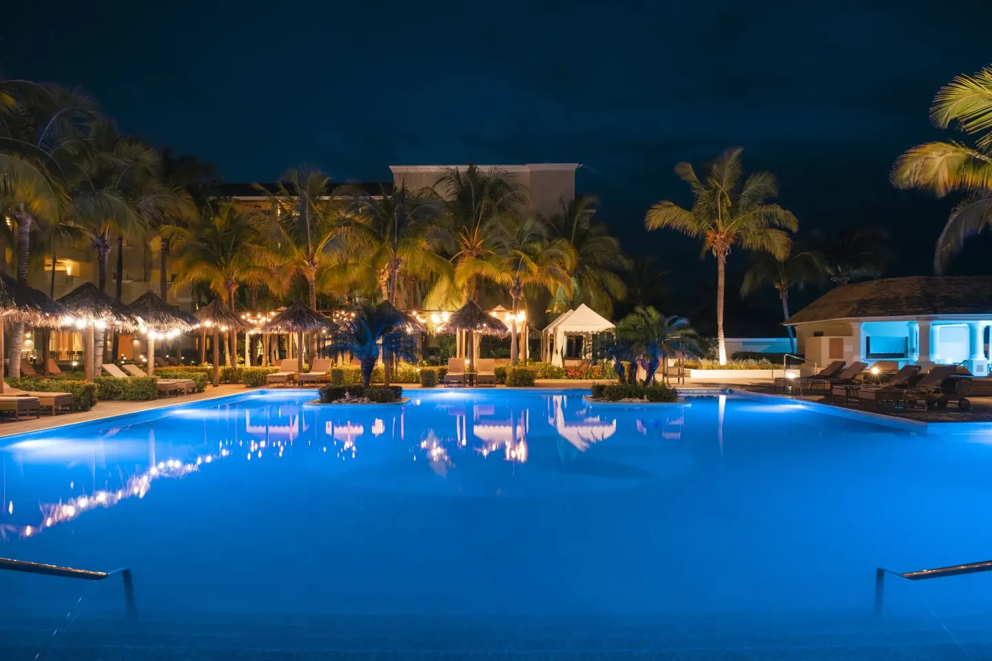 Illuminated resort pool at night at JOIA Rose Hall by Iberostar.