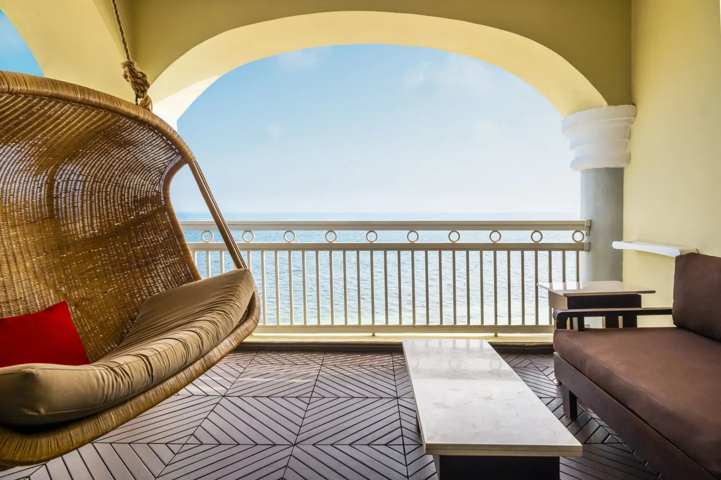 Oceanfront balcony with hanging chair and lounge seating at JOIA Rose Hall by Iberostar.