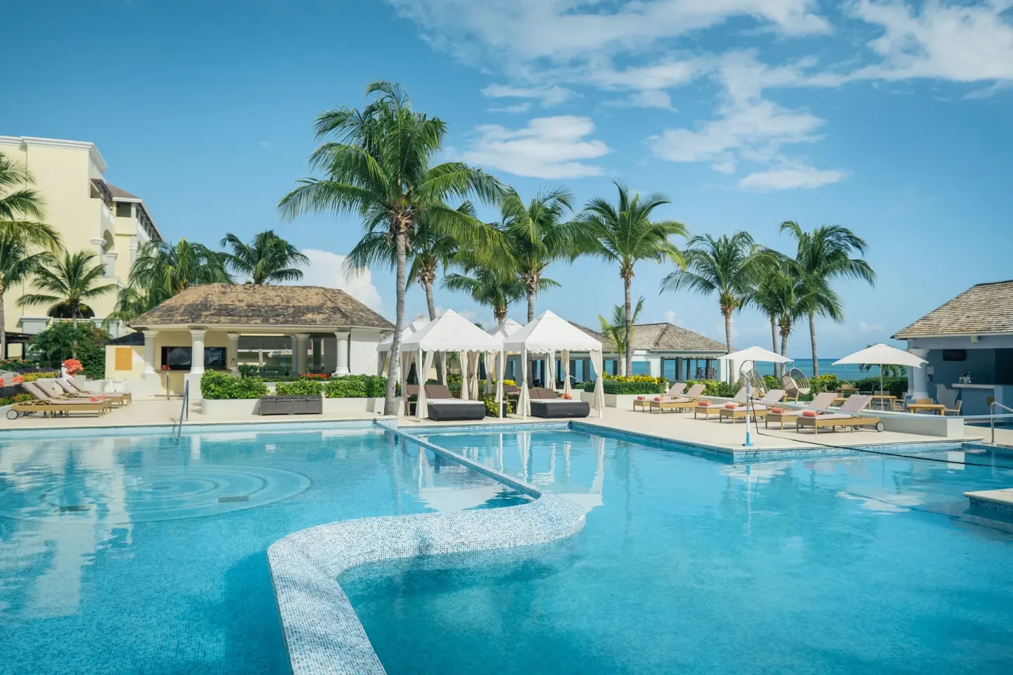 Palm-lined pool terrace with loungers at JOIA Rose Hall by Iberostar.