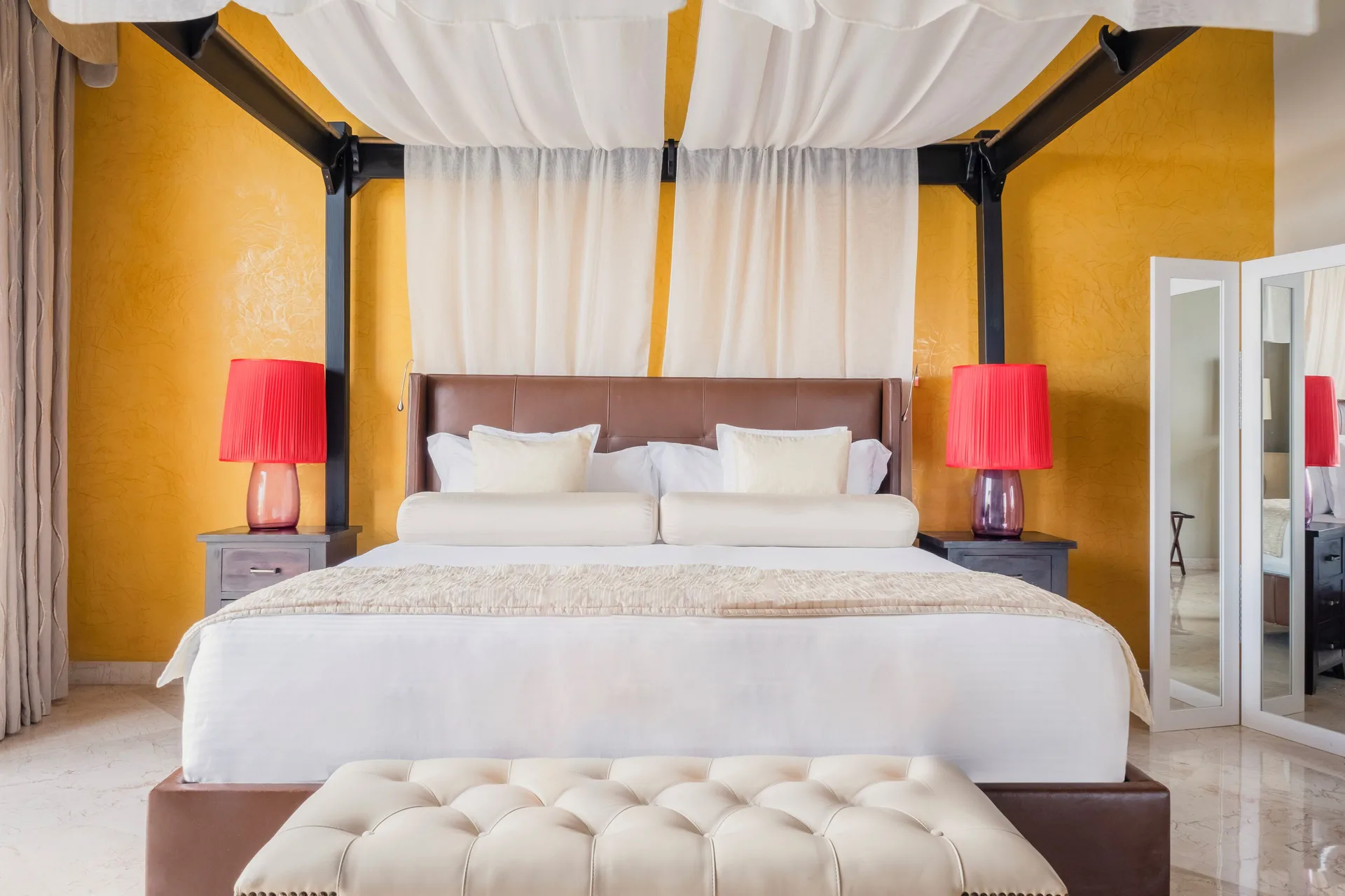 Canopy king bed with red bedside lamps at JOIA Rose Hall by Iberostar.