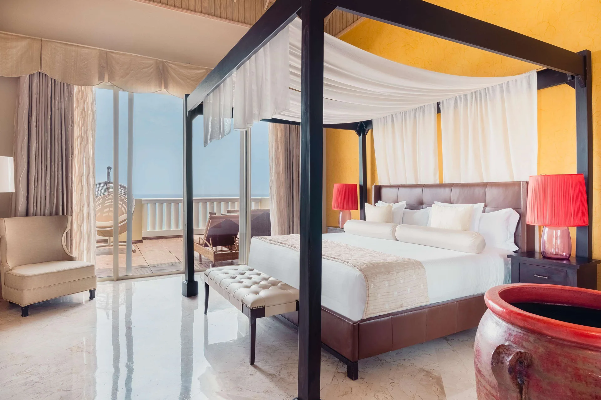 Four-poster king bed and balcony in a suite at JOIA Rose Hall by Iberostar.