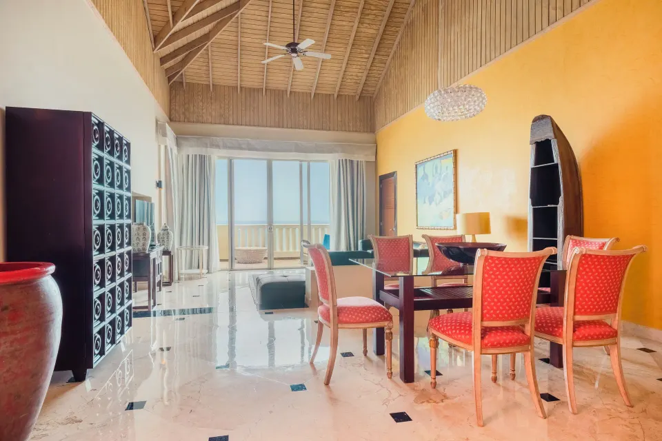 Suite living and dining area with vaulted wood ceiling at JOIA Rose Hall by Iberostar.